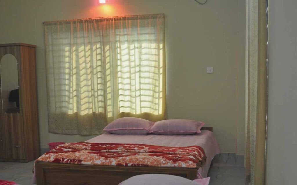A double bed room at Garden View Guest House with sheer curtains and a wooden wardrobe