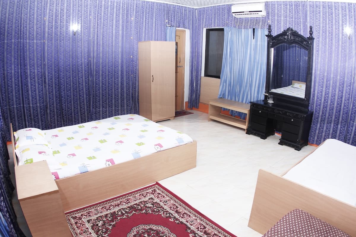 Guest room with purple striped wallpaper and curtains, a single bed, wall-mounted AC unit, and a black carved dresser with mirror