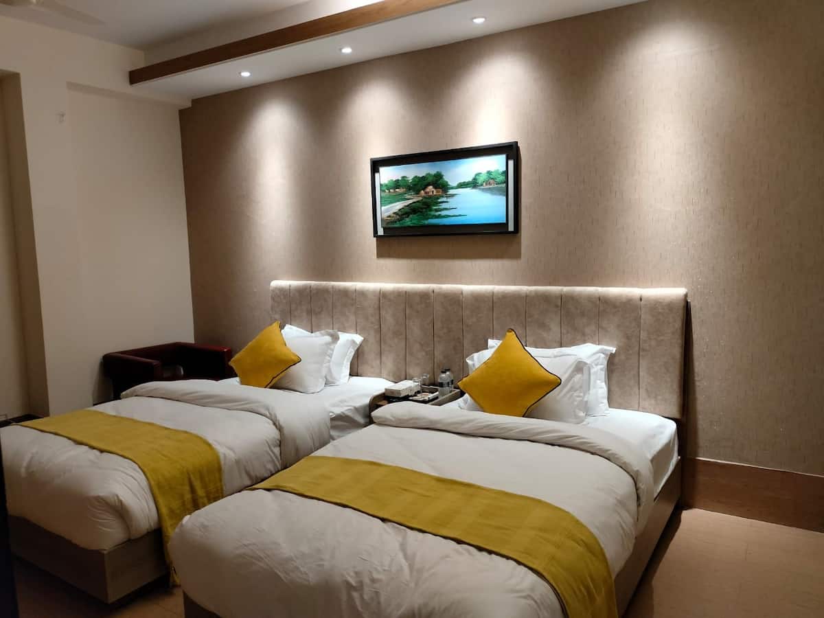 Hotel Taj Metro twin room with two single beds, yellow throws, and a framed landscape painting