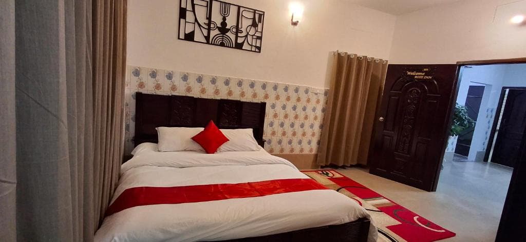 A double room at Rose Inn with a carved wood headboard and the room door open to the corridor