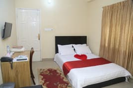 The Couple Duplex room at Sreemangal Inn with a black headboard, red bed runner, and patterned curtains