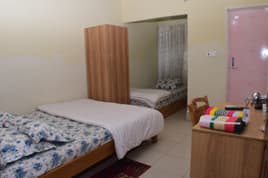 The Family Duplex room at Sreemangal Inn with two beds, a wooden wardrobe, and a study desk