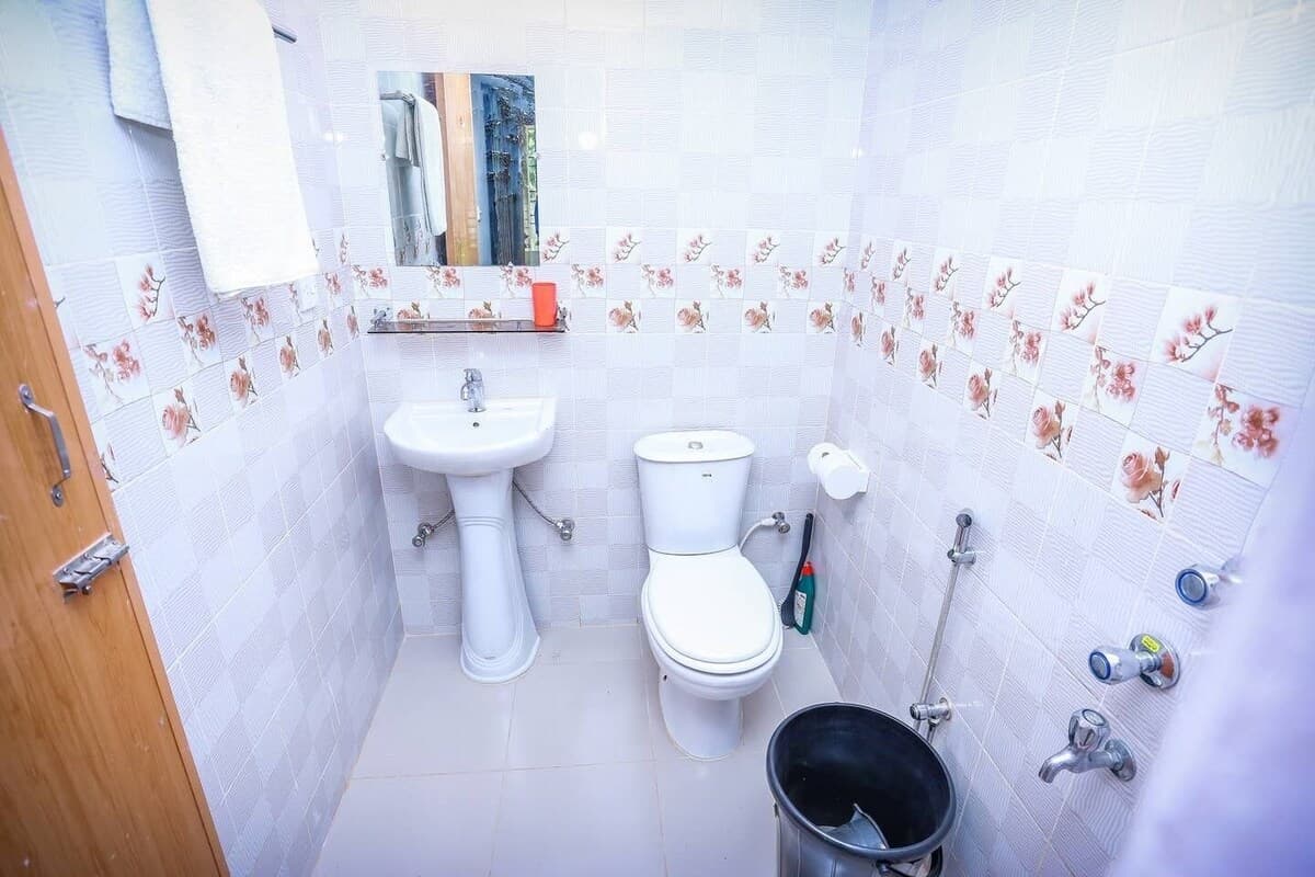 En-suite bathroom with floral-tiled walls, pedestal sink, and Western toilet